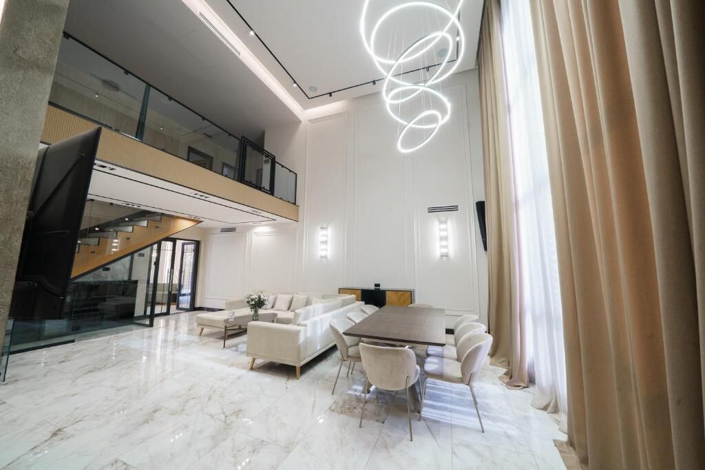 A spacious, modern interior with a dining area, sofas, and a staircase.