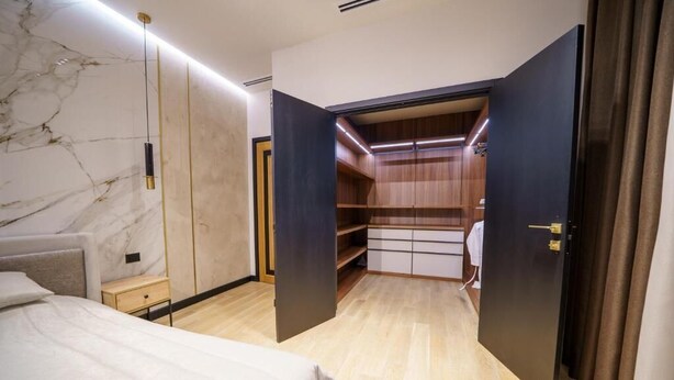 Ein Schlafzimmer mit Bett, Nachttisch, Kleiderschrank und begehbarer Kleiderabteilung.