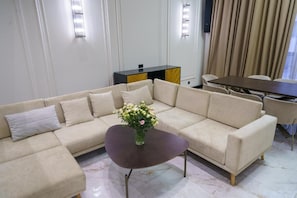 A modern living room with a beige sectional sofa, a dark coffee table, and a dining area with a table and chairs. - Lux Villa In The Heart of Yerevan Verin Antarayin (Yerevan)