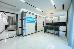 A modern kitchen with a marble countertop, a built-in TV, and a bar area with stools. - Lux Villa In The Heart of Yerevan Verin Antarayin (Yerevan)