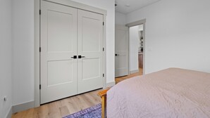 Ein Schlafzimmer mit einem Bett, einem Kleiderschrank und einem Badezimmer im Hintergrund.