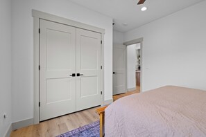 Quarto com cama, guarda-roupa e banheiro visível ao fundo.