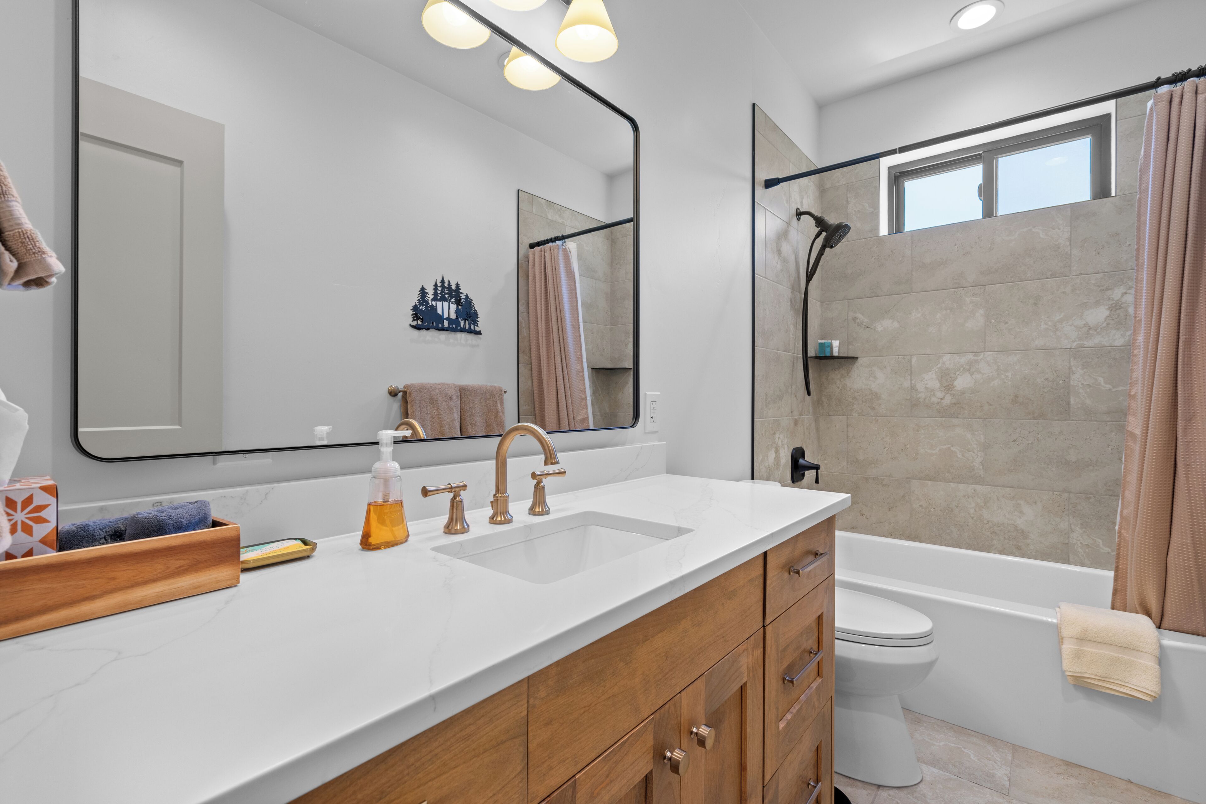A modern bathroom with a white vanity, a large mirror, a shower with a glass door, and a toilet.