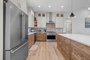 A modern kitchen with stainless steel appliances, wooden cabinets, and a central island. - Brand-New Mountain Retreat Sleeps 8 (Palisades)