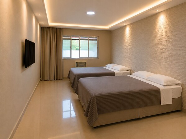A hotel room with two beds, a television on the wall, and a window with curtains.