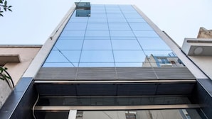 Un edificio moderno con fachada de vidrio y una escalera metálica que baja a un nivel inferior.