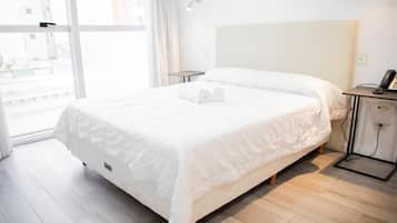 Una habitación de hotel con una cama grande, una mesita de noche con lámpara y vistas por la ventana.