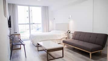 A modern hotel room with a bed, sofa, desk, and chair.