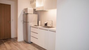 Una cocina moderna con armarios blancos, horno integrado y un lavamanos en la encimera.