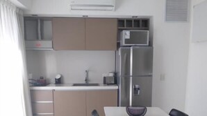 Una cocina moderna con refrigerador, microondas y comedor con mesa y sillas.