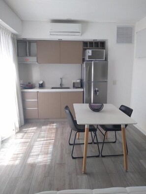 Una cocina moderna con refrigerador, microondas y comedor con mesa y sillas.