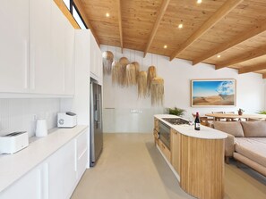 Eine moderne Küche mit weißen Schränken, einem eingebauten Backofen und einer Holzbalkendecke.