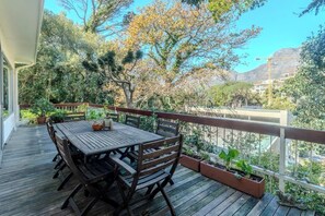 Une terrasse en bois avec une table et des chaises, entourée de plantes en pot et offrant une vue panoramique.