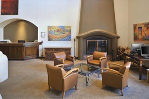 Eine Lobby mit Ledersesseln, einem Kamin, einem Empfangstresen und Kunstwerken an den Wänden.