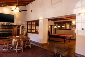 Ein Raum mit Poolbillard, Jukebox, Fernseher und Deckenventilator.