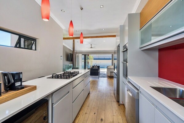 A modern kitchen with a central island, stainless steel appliances, and pendant lighting. - Sea Point Gem with Private Pool & Fireplace (Cape Town)