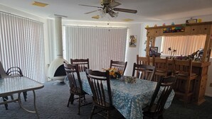 A dining area with a round table, chairs, a ceiling fan, and a wood-burning stove. - Parker Strip House Riverfront, Dock, Patio & view!  2-bedroom house with AC/ SPA (Parker)