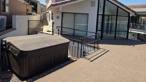 A residential building with a covered patio, a hot tub, and a large window. - Parker Strip House Riverfront, Dock, Patio & view!  2-bedroom house with AC/ SPA (Parker)