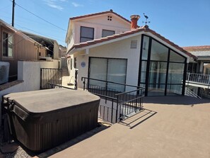 Ein Wohngebäude mit überdachter Terrasse, Whirlpool und großem Fenster.