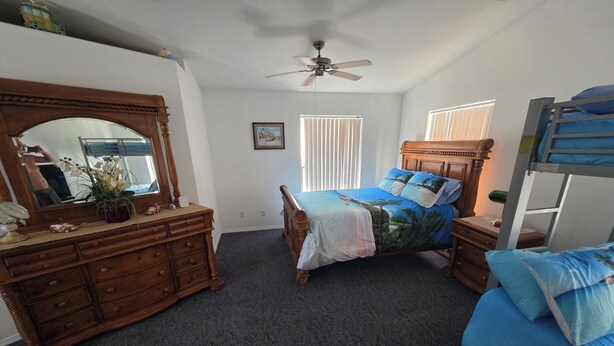 A bedroom with a wooden dresser, a bed with blue bedding, a bunk bed, a ceiling fan, and a window with blinds. - Parker Strip House Riverfront, Dock, Patio & view!  2-bedroom house with AC/ SPA (Parker)