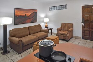 Ein Wohnzimmer mit Sofa, Sessel, Tisch, Lampe und einem Bild an der Wand.