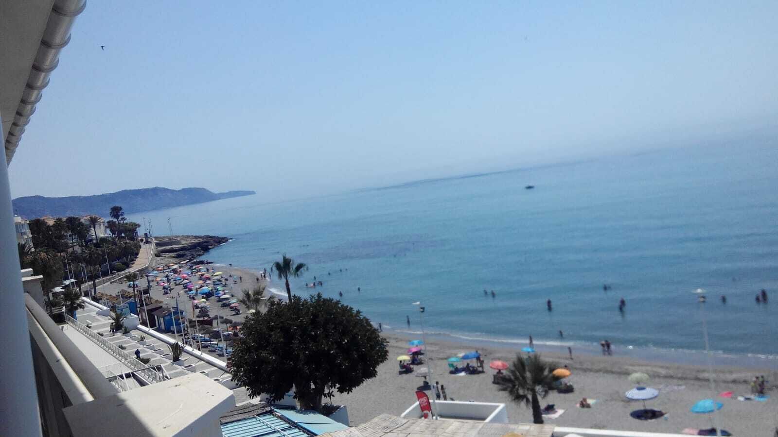 Una playa con sombrillas, gente y una vista despejada del mar.