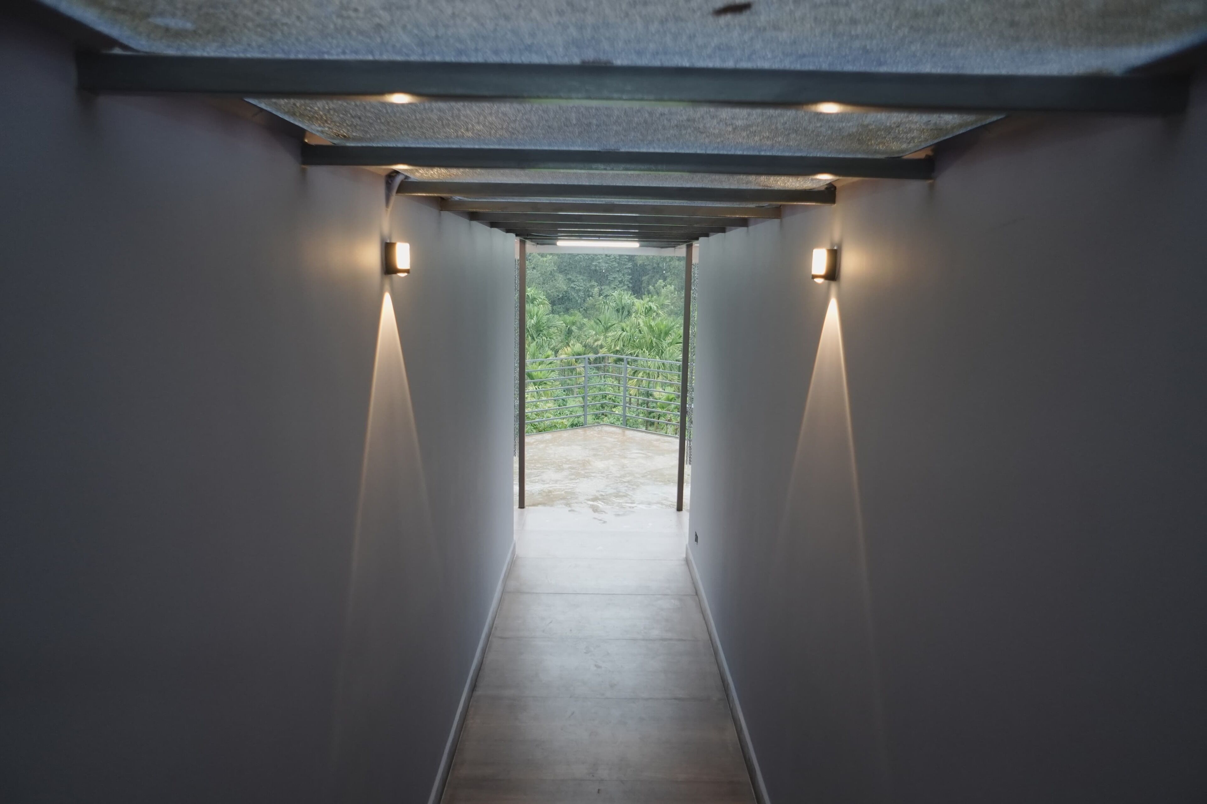 Un pasillo con vistas a un espacio exterior, con un techo que incluye un tragaluz y luces empotradas en la pared.