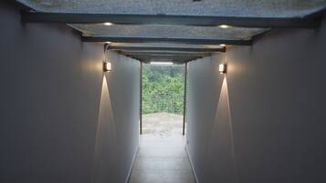 Un pasillo con vistas a un espacio exterior, con un techo que incluye un tragaluz y luces empotradas en la pared.