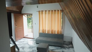 Una habitación con sofá, una mesita, una puerta y una ventana con cortinas.