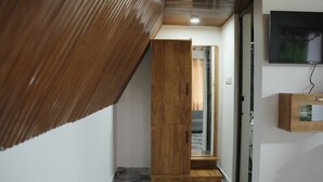 Un pasillo con un armario de madera, una puerta de vidrio y un televisor montado en la pared.