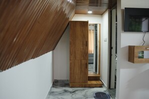 A hallway with a wooden wardrobe, a glass door, and a television mounted on the wall.