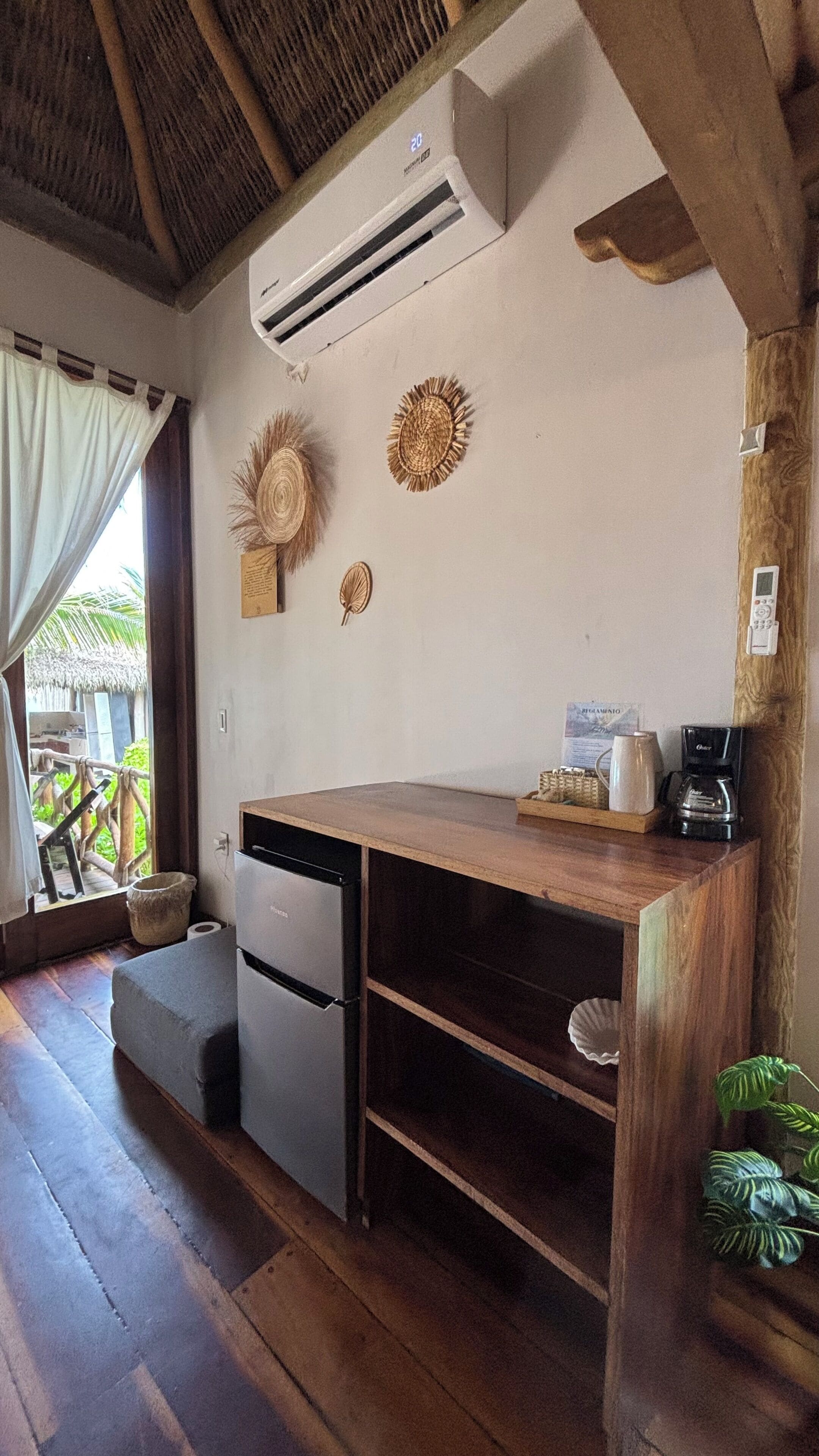 A compact kitchen with a refrigerator, a coffee maker, and a wooden counter.