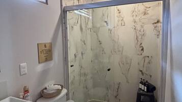 Un baño con inodoro, lavabo y cabina de ducha.
