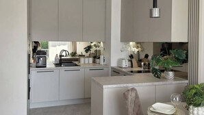 A modern kitchen with a central island, pendant lighting, and a dining area with a table and chairs.