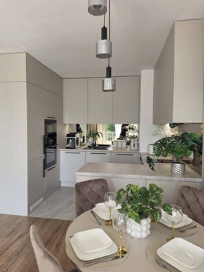 A modern kitchen with a central island, stainless steel appliances, and a hanging light fixture. - Nowy Apartament Blisko Suntago Mszczonow (Mszczonow)