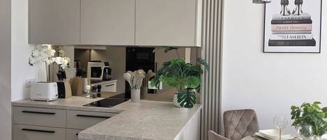 Una cocina moderna con una isla central, una zona de comedor con mesa y sillas, y un cuadro en la pared.