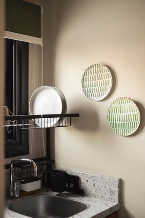 A kitchen with a black dish rack, a granite countertop, and three decorative plates on the wall. - Solé ORO Rooftop Studio I Nesty Hospitality (Al Maadi)