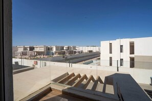 Eine Dachterrasse mit freiem Blick auf die angrenzenden Gebäude, einem Pool und einer Treppe, die nach unten führt.
