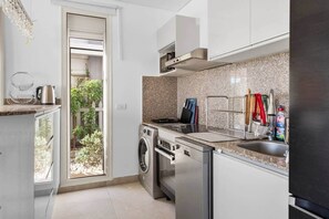 Eine moderne Küche mit Waschmaschine, Spüle und Fenster mit Blick auf einen Garten.