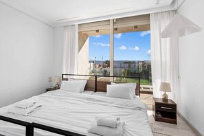 A modern bedroom with a large bed, a nightstand, and a view of a balcony. - Casa Maraya with private pool I Nesty Hospitality (Second Hurghada)