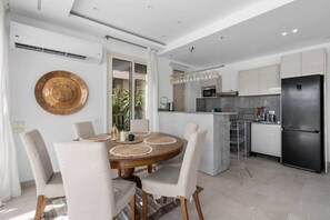 A modern kitchen with white cabinets, a stainless steel refrigerator, and a dining area with a round table and chairs. - Casa Maraya with private pool I Nesty Hospitality (Second Hurghada)