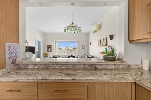 A modern kitchen with a marble countertop, wooden cabinets, a chandelier, and a view of the outdoors. - The Sandy Feet. Part II - Nesty Hospitality (Hurghada)