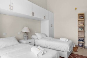 Ein Hotelzimmer mit zwei Betten, einem Nachttisch mit Lampe, einem Kleiderschrank und einem Bücherregal.