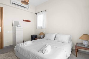 A hotel room with a bed, bedside tables, a lamp, a wardrobe, and an air conditioning unit. - The Sandy Feet. Part II - Nesty Hospitality (Hurghada)