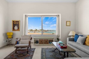 Ein Wohnzimmer mit Blick auf den Strand, inklusive Sofa, Sessel, Couchtisch und Lampe.