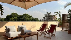 A rooftop terrace with a sofa, two lounge chairs, a table, and a large umbrella. - Solé Verde Rooftop Studio I Nesty Hospitality (Al Maadi)