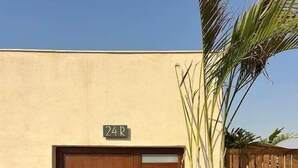 A wooden door with a number plate, a potted plant, and a wooden fence. - Solé Verde Rooftop Studio I Nesty Hospitality (Al Maadi)