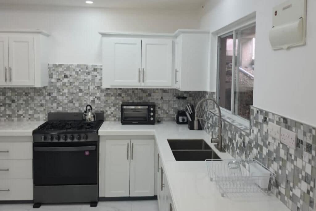 A modern kitchen with white cabinets, a gas stove, a microwave, and a tiled backsplash.