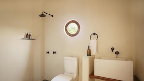 A bathroom with a toilet, a shower, a sink, and a window. - Angelique s Boutique Spa & Suites (Troncones)