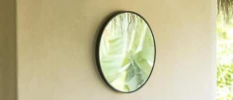 A bathroom with a white sink, a round mirror, and a plant.